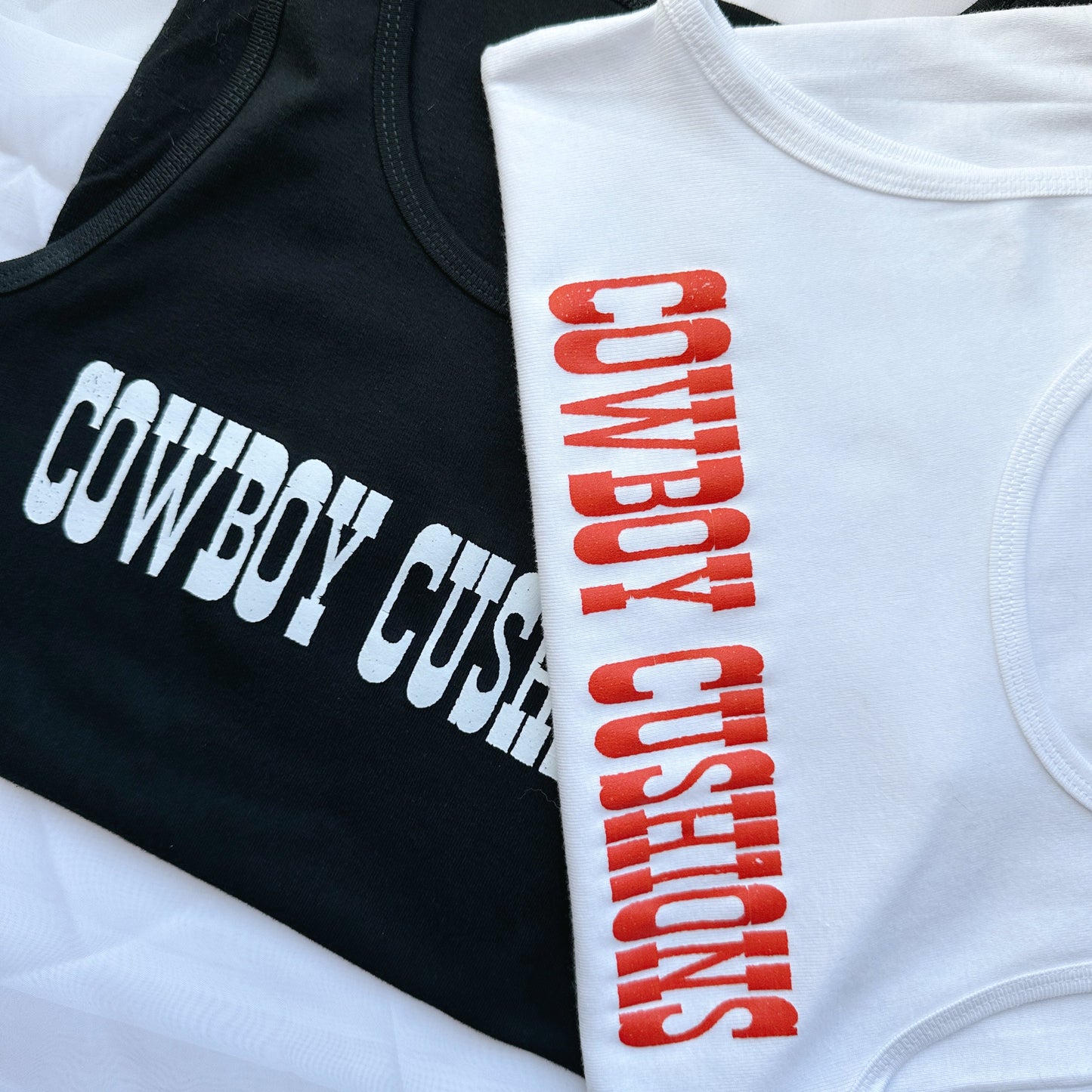 white and black tank tops with cowboy cushions across the chest