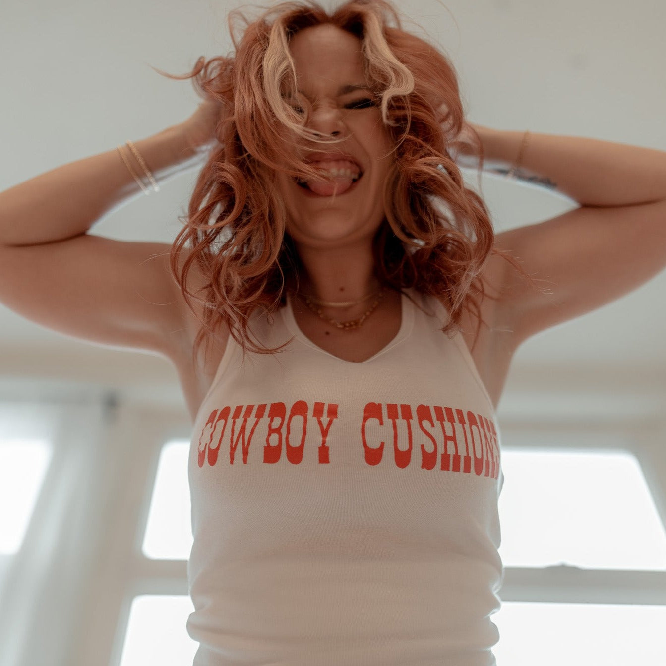 white baby ribbed tank top with red cowboy cushions across the chest