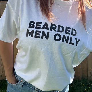 White tshirt on a model that says BEARDED MEN ONLY in bold black letters paired with a pair of jean shorts 